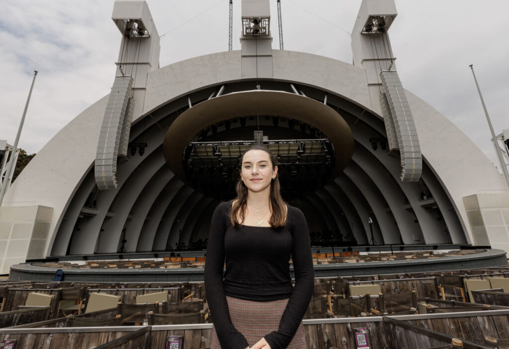 Young lady standing in box seat in front of empty stage at the Hollywood Bowl