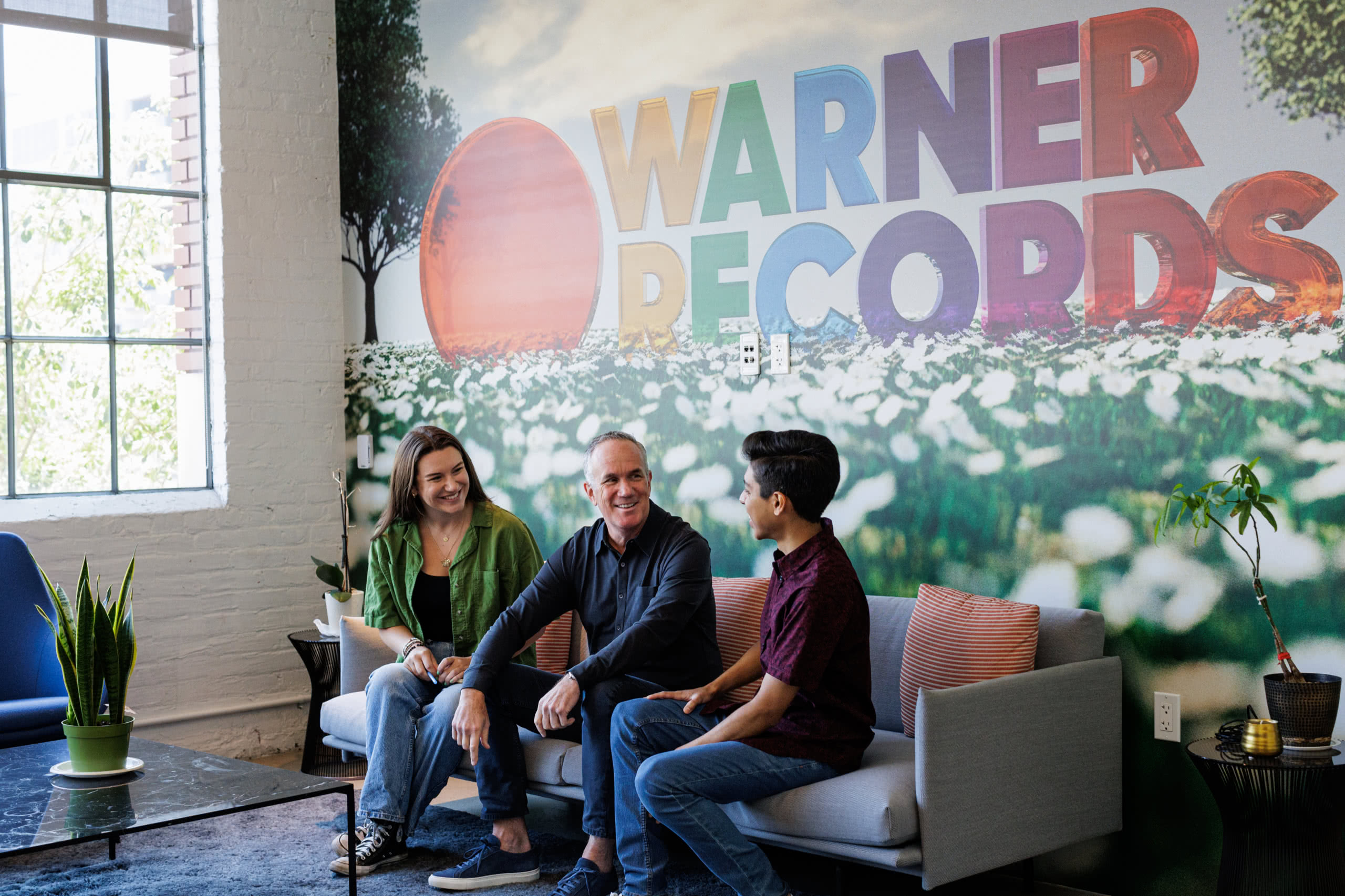 Young man conversing with adults in Warner Records waiting area